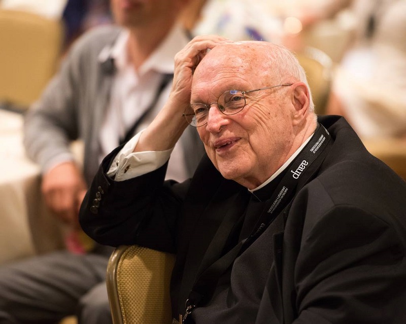 Fr. Haig smiles with a hand to his head